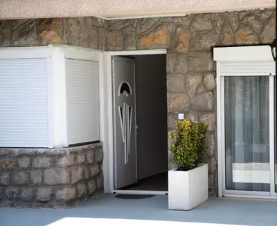 a front door of a house with a stone wall at FOR-A Apartmani in Becici