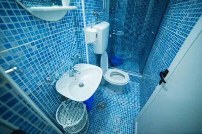 a blue tiled bathroom with a toilet and a sink at FOR-A Apartmani in Becici