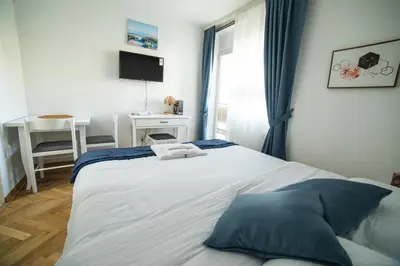 a bedroom with a large white bed with blue pillows at FOR-A Apartmani in Becici
