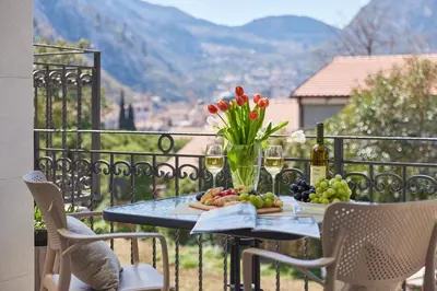 a table with fruit and flowers on a balcony at Stanisic Family Apartments in Kotor