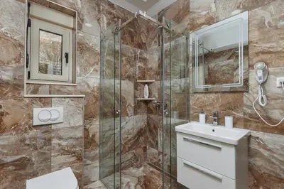 a bathroom with a shower and a sink and a mirror at Stanisic Family Apartments in Kotor