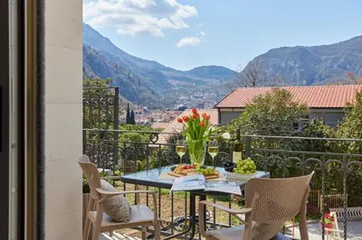 a table with a bowl of fruit and flowers on a balcony at Stanisic Family Apartments in Kotor