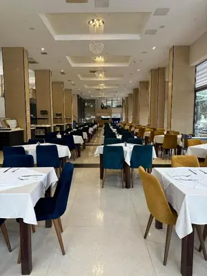 a dining room with white tables and blue chairs at Vile Oliva Hotel & Resort in Petrovac na Moru