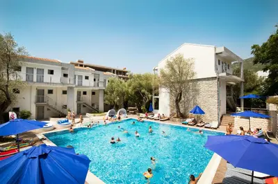 a pool with people in it with blue umbrellas at Vile Oliva Hotel & Resort in Petrovac na Moru