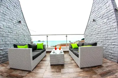 a patio with two couches and a table with green pillows at Vile Oliva Hotel & Resort in Petrovac na Moru