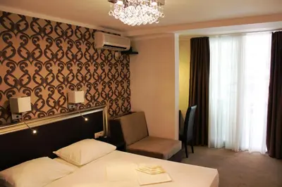 a hotel room with a bed and a chandelier at Vile Oliva Hotel & Resort in Petrovac na Moru