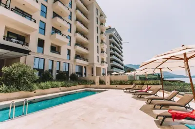 a pool with chairs and umbrellas next to a building at Luxury apartment Casa Al Mare in Rafailovici