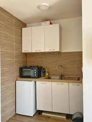a kitchen with white cabinets and a sink and a microwave at JG Studio apartment in Vranjina