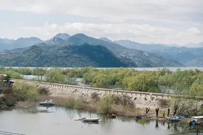 a river with boats in it with mountains in the background at JG Studio apartment in Vranjina