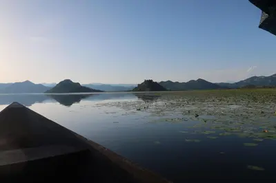 a boat on a lake with mountains in the background at JG Studio apartment in Vranjina