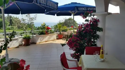 a patio with a table and an umbrella and flowers at Firenze Apartments in Ulcinj