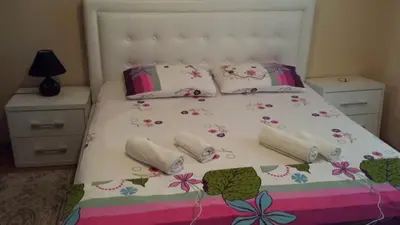 a bedroom with a white bed with flowers and pillows at Firenze Apartments in Ulcinj