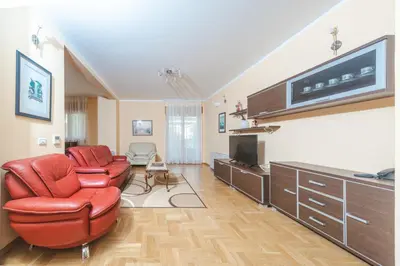 a living room with a red chair and a flat screen tv at Hotel Stella di Mare in Budva