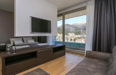 a room with a desk with a television and a couch at Apartments Lux in Budva
