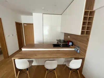 a kitchen with a counter with four white chairs at Apartments Lux in Budva