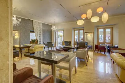 a waiting room with tables and chairs and windows at Hotel Vardar in Kotor