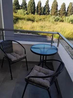 a glass table and two chairs on a balcony at Apartment Long beach in Ulcinj