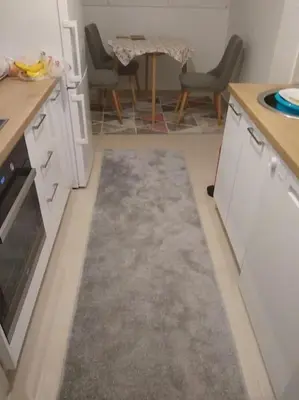 a kitchen with a rug on the floor and a table at Main bus station apartment in Podgorica