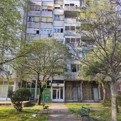 an apartment building in front of a park with trees at Main bus station apartment in Podgorica