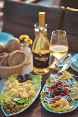 a table with two plates of food and a glass of wine at Hotel WGrand in Petrovac na Moru