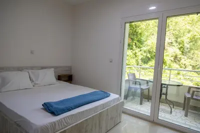 a bedroom with a bed and a balcony with a table at Villa Erik in Ulcinj