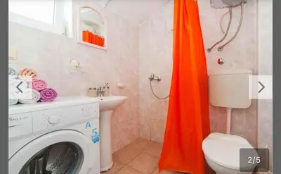 an orange shower curtain in a bathroom with a washing machine at Maki Apartments - Plavi Horizonti Beach in Tivat