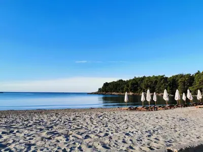a group of umbrellas and chairs on a beach at Maki Apartments - Plavi Horizonti Beach in Tivat
