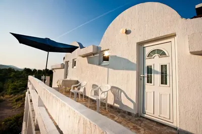 a white building with a door and chairs and an umbrella at Maki Apartments - Plavi Horizonti Beach in Tivat