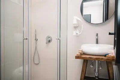 a bathroom with a shower with a sink and a mirror at KAAB Boutique Hotel in Ulcinj