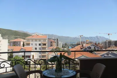 a table on a balcony with a view of a city at Diva Petra Apartments in Budva