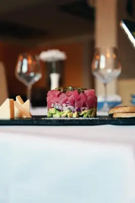 a plate of food on a table with wine glasses at Monte Casa SPA & Wellness in Petrovac na Moru