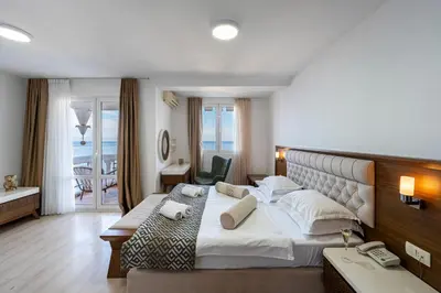 a hotel room with a large bed and a phone at Hotel Adrović in Sveti Stefan