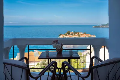 a table on a balcony with a view of the ocean at Hotel Adrović in Sveti Stefan