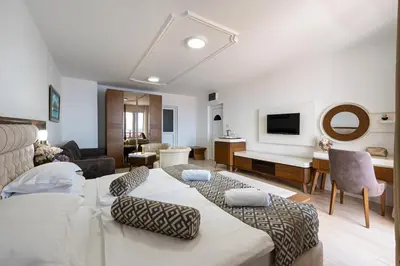 a bedroom with two beds and a living room at Hotel Adrović in Sveti Stefan
