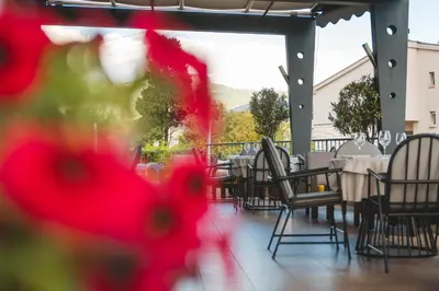 a restaurant with tables and chairs with red flowers at Hotel Keto in Podgorica