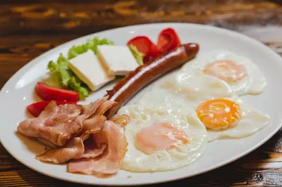 a plate of breakfast food with eggs bacon and vegetables at Hotel Keto in Podgorica