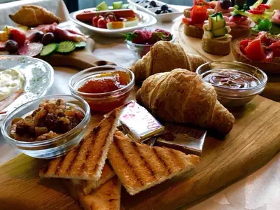 a wooden board with bread and other food on a table at Hotel Keto in Podgorica