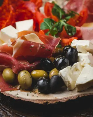 a plate of food with cheese olives and other foods at Hotel Keto in Podgorica