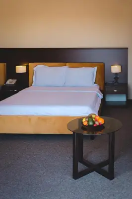 a bedroom with a bed and a table with a bowl of fruit at Hotel Keto in Podgorica