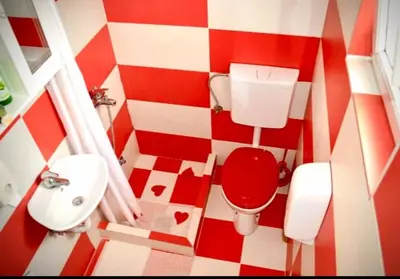 a red and white bathroom with a toilet and sink at Apartmani LANA Podgorica in Podgorica
