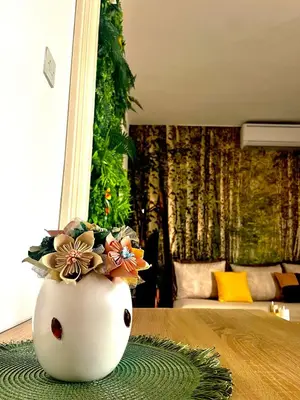a white vase with flowers in it on a table at Apartmani LANA Podgorica in Podgorica
