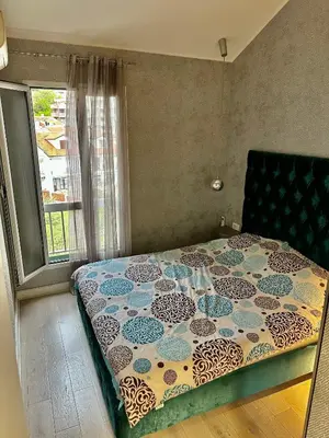 a bedroom with a bed with a flowered comforter and a window at Lux Apartment Budva in Budva