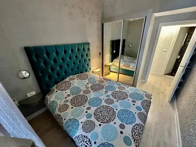 a bedroom with a bed with a blue headboard and a mirror at Lux Apartment Budva in Budva
