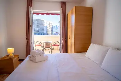 a bedroom with a bed and a balcony with a table at Villa Maxima Budva in Budva