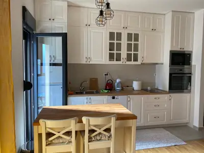 a kitchen with a wooden table and white cabinets at Studio Z in Podgorica