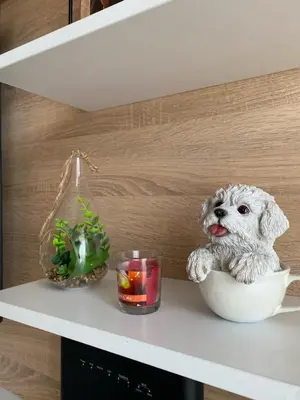 a stuffed dog in a bowl on a shelf with a candle at Apartman DVA SRCA in Bar