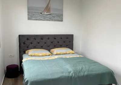 a bed with a green comforter and two pillows at Apartment SuSe in Dobra Voda