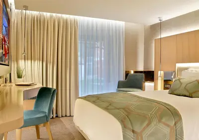 a hotel room with a bed and two chairs and a desk at Maestral Resort & Casino in Budva