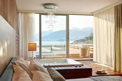 a living room with a bath tub and a large window at Maestral Resort & Casino in Budva