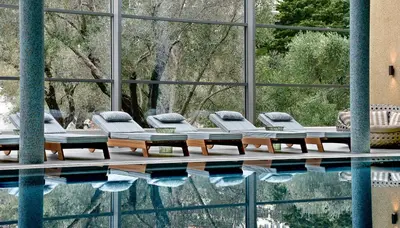 a swimming pool with lounge chairs and a large window at Maestral Resort & Casino in Budva